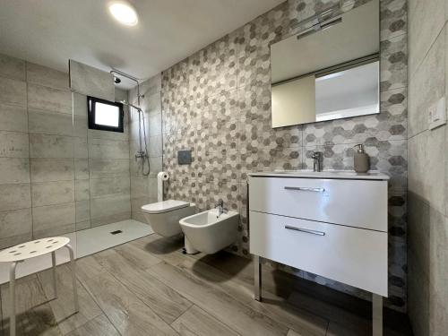 bagno con servizi igienici, lavandino e specchio di Casa Maria Cecília a Jávea