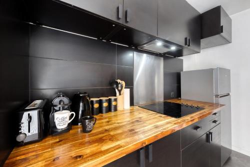 a kitchen with a wooden counter top and black cabinets at LE GARDEN -MAISON-2Parking-Jardin-Terrasse-Babyfoot-wifi in Cergy