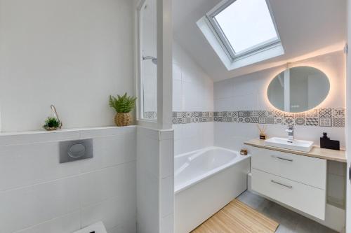La salle de bains est pourvue d'un lavabo, d'une baignoire et d'une fenêtre. dans l'établissement LE GARDEN -MAISON-2Parking-Jardin-Terrasse-Babyfoot-wifi, à Cergy