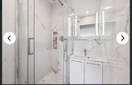 une salle de bain blanche avec une douche et un lavabo dans l'établissement Villa de charme complètement rénové, à Meudon