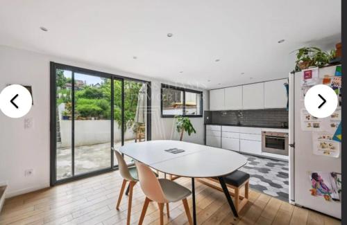 - une cuisine avec une table et des chaises blanches dans la chambre dans l'établissement Villa de charme complètement rénové, à Meudon