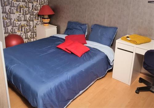 a bedroom with a blue bed with a desk and a red pillow at Chambre spacieuse à Sartrouville in Sartrouville