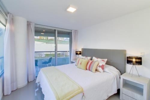 a bedroom with a bed and a large window at Oceana Suites en Isabel, frente a playa Mansa in Punta del Este