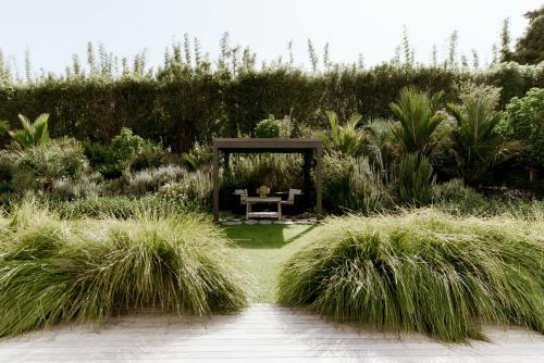 a garden with a table and some tall grass at The Villa at Bali Garden Matakana in Omaha