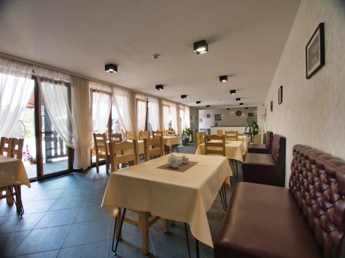 un comedor con mesas, sillas y ventanas en Nikol Guest House en Bukovel