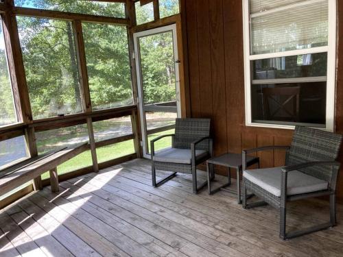 a screened in porch with two chairs and windows at Redbud Cottage in Maumee