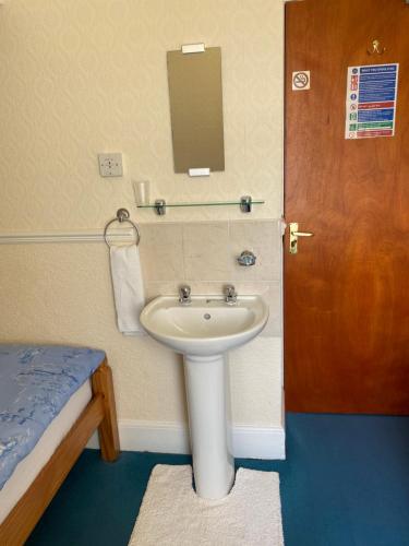 a bathroom with a sink and a door and a bed at The Laurels in Blackpool