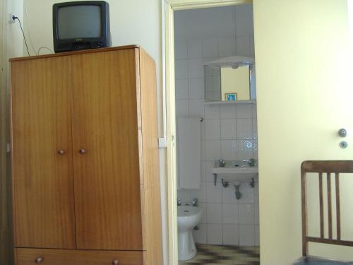 a bathroom with a toilet and a television on top of a cabinet at Residência Ideal in Coimbra