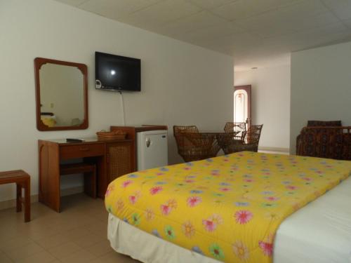 a bedroom with a bed and a desk and a mirror at Santa Barbara Arauca in Arauca