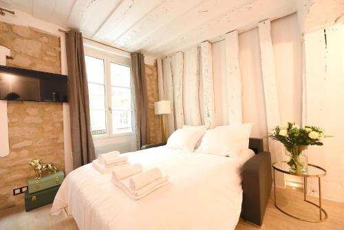 Cosy flat - Saint germain في باريس: غرفة نوم بسرير ابيض كبير عليها مناشف