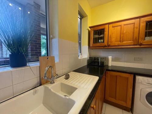 a kitchen with a white sink and a window at Elegant Weybridge Apartment near Train Station in Oatlands Park