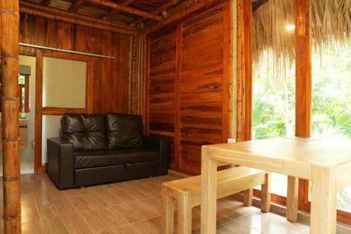 a living room with a leather chair and a table at Tiny Houses Unique Tayrona - Dentro del Parque Tayrona in El Zaino