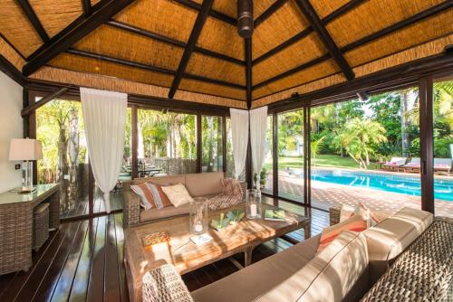 una sala de estar de planta abierta con una piscina en el fondo en Villa in a palm tree plantation en Marbella