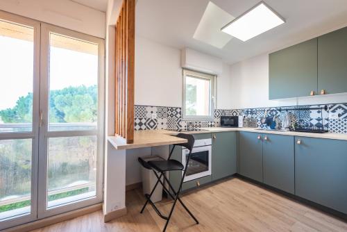 uma cozinha com armários azuis e uma mesa com uma cadeira em Studio cosy au pied de la plage em Carry-le-Rouet