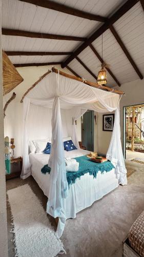a bedroom with a white bed with a canopy at Pousada Céu de Corumbau in Corumbau