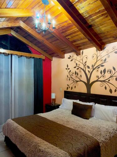a bedroom with a bed with a tree mural on the wall at Hotel Real de la Sierra in Mazamitla