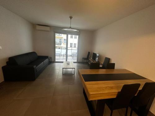 un salon avec un canapé noir et une table dans l'établissement Superbe Appartement terrasse 2P à 5 min à pied du vieux Nice, du port et du Tram, à Nice