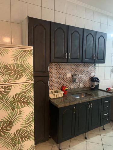 cocina con armarios negros y nevera en Ótimo Apartamento Frente ao Mar em Mongaguá, en Mongaguá