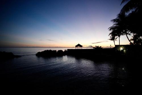 a sunset over a body of water with a gazebo at Idyllic Beachfront Condo in Ocho Rios