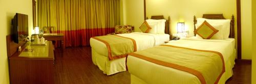 a hotel room with two beds and a television at Ramada Jamshedpur Bistupur in Jamshedpur
