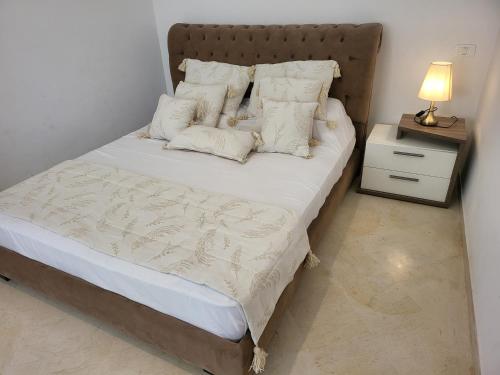 een slaapkamer met een bed met witte lakens en kussens bij Lido Jinen Hammamet in Hammamet