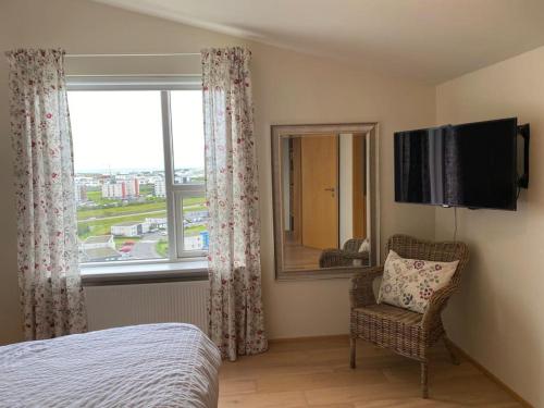 a bedroom with a bed and a window and a chair at Pent house dublex with amazing city and Ocean views for 4 rooms 6 people in Reykjavík