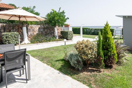 a patio with a table and an umbrella and some bushes at Villa Mare in Mákri