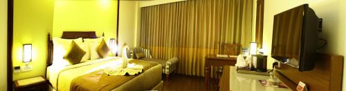 a hotel room with a bed and a television at Ramada Jamshedpur Bistupur in Jamshedpur