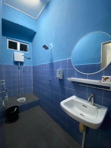 La salle de bains bleue est pourvue d'un lavabo et d'un miroir. dans l'établissement RumahRehatAndCo, à Kampong Molek
