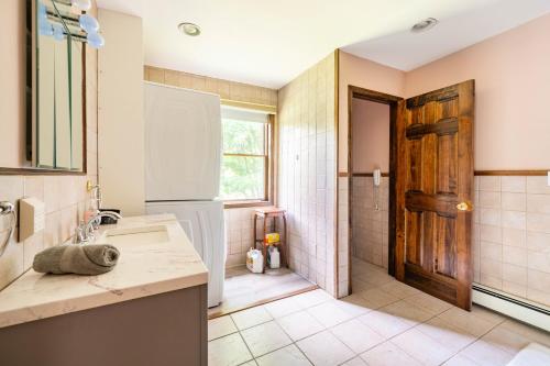 a bathroom with a sink and a shower and a door at Bethel Woods Retreat - wPool, Hot Tub & Arcade! in Mongaup Valley