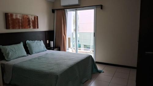 a bedroom with a bed and a large window at Studio pé na areia, vista, internet e ar in Macaé