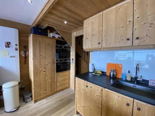 une cuisine avec des armoires en bois et un comptoir noir dans l'établissement Alpe d'Huez Houses - Chalet des Roches - Duplex, SUR les pistes de 3 chambres !, à L'Alpe-d'Huez