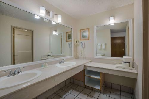 uma casa de banho com 2 lavatórios e um espelho grande em Suburban Studios Canon City em Canon City