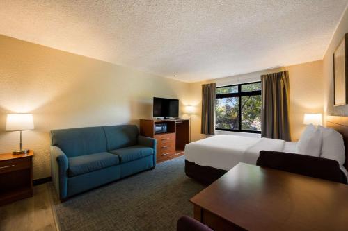 um quarto de hotel com uma cama e um sofá azul em Suburban Studios Canon City em Canon City