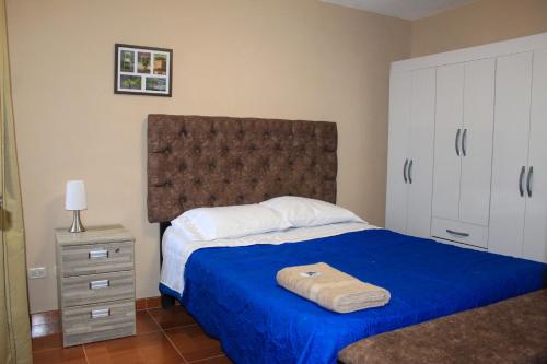 a bedroom with a large bed with a blue blanket at Departamento Chiclayo Perú in Chiclayo