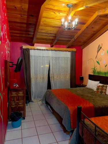 a bedroom with a bed with red walls and a ceiling at Hotel Real de la Sierra in Mazamitla