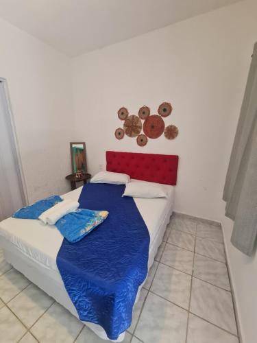 カノア・ケブラーダにあるPousada Capitolio 02 Canoa Quebradaのベッドルーム1室(青い毛布と壁にプレートが付いたベッド1台付)