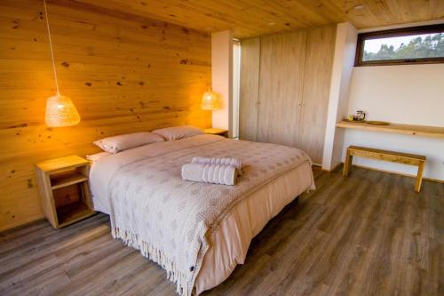 1 dormitorio con 1 cama en una habitación de madera en Lafk Lodge, en Pichilemu
