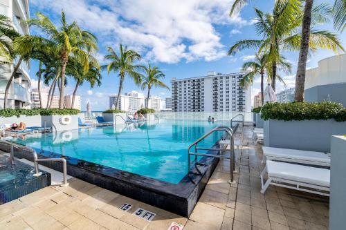 a swimming pool with palm trees and a resort at Beachfront Luxury 2BR 2BA, Sleeps 6, Resort Access - Horizon by HomeStakes in Fort Lauderdale
