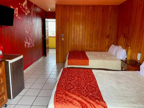 a hotel room with two beds and a television at Hotel Real de la Sierra in Mazamitla