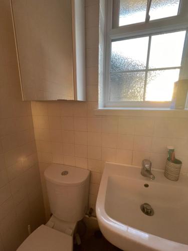 a bathroom with a toilet and a sink and a window at Wardown Place - Spacious 3 Bed House available for short term or long term Rental in Luton