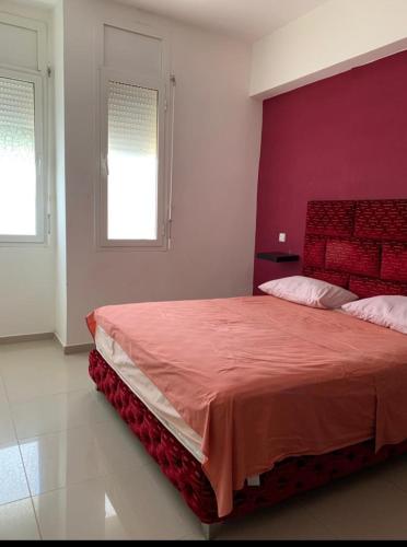 - une chambre avec un grand lit et une tête de lit rouge dans l'établissement Massira 1, à Fnideq