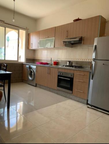 - une cuisine avec des placards en bois et un réfrigérateur blanc dans l'établissement Massira 1, à Fnideq