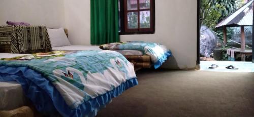 a bedroom with two beds and a window with green curtains at Bungalow Paer Doe in Sembalunbumbung