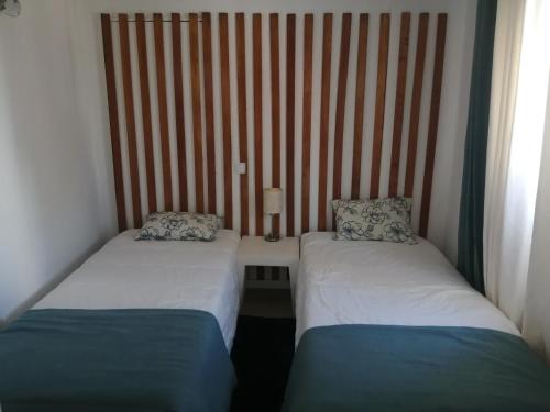 2 camas individuales en una habitación con una pared a rayas en Retiro dos sonhos en Porches