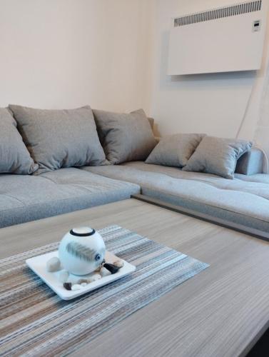 Una sala de estar con un sofá y un jarrón en un plato. en Green Forest Lux Apartman, en Zlatibor