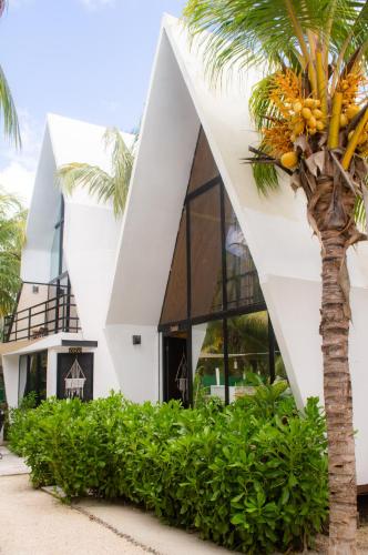 a building with a palm tree in front of it at Xtambaa Cabins & Spa Only Adults in El Cuyo