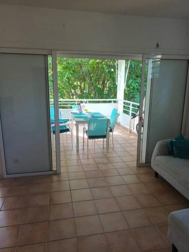 a living room with a patio with a table and chairs at Grand appartement duplex in Baie-Mahault