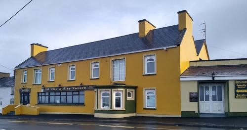 um edifício amarelo no lado de uma rua em KATHLEENS COTTAGE em Quilty