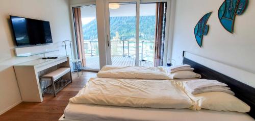 Habitación con 2 camas, escritorio y TV. en Scarlett, en Davos